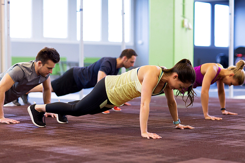 fitness, sport, exercising, training and healthy lifestyle concept - group of people doing straight arm plank in gym