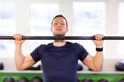 sport, fitness, exercising and people concept - man doing pull-ups on horizontal bar in gym