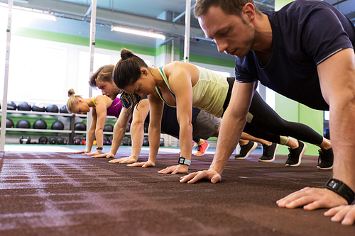 fitness, sport, exercising, training and healthy lifestyle concept - group of people doing straight arm plank in gym