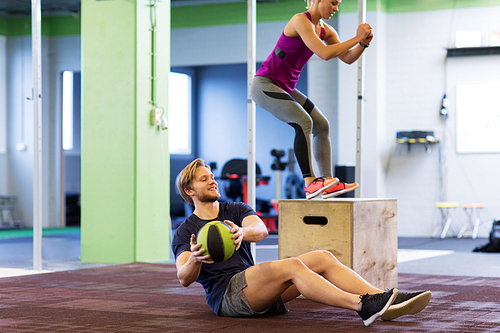 fitness, sport, training, exercising and people concept - happy woman and man with medicine ball doing curl ups and box jumps in gym