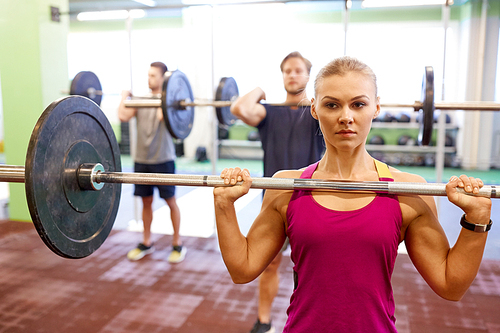 fitness, sport, training, exercising and lifestyle concept - group of people with barbells doing shoulder press in gym