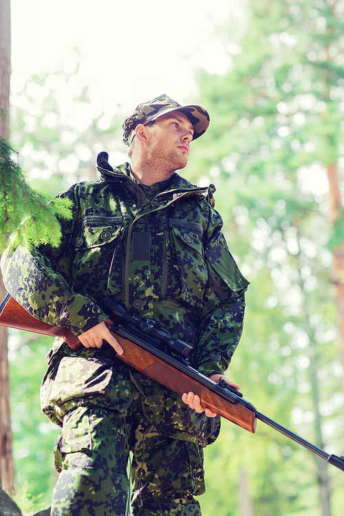 hunting, war, army and people concept - young soldier, ranger or hunter with gun in forest