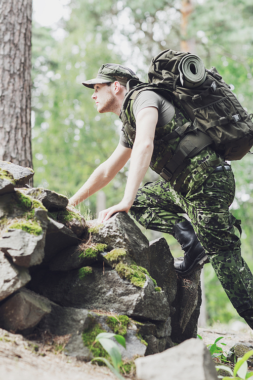 war, hiking, army and people concept - young soldier or ranger with backpack walking in forest