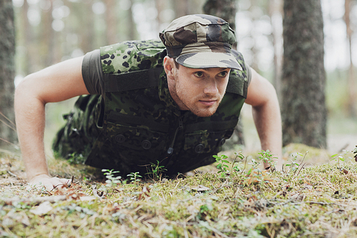 war, army, training and people concept - young soldier or ranger wearing military uniform doing push-ups in forest