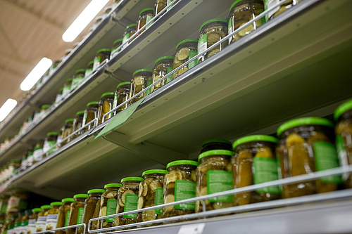 sale, shopping, food and consumerism concept - jars of pickles on grocery or supermarket shelves