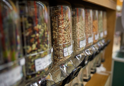 sale and eco food concept - row of jars with nuts and seeds at grocery store