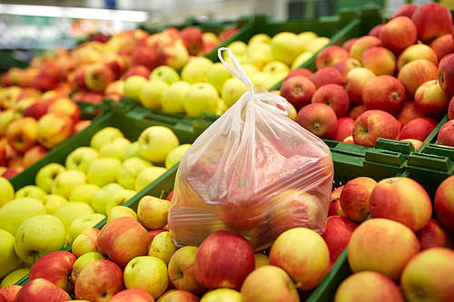 fruits, harvest, food and sale concept - bag of ripe apples at grocery store or market