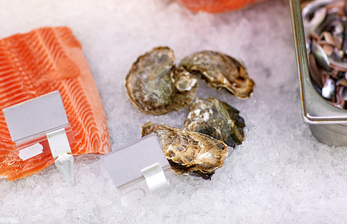 seafood, sale and food concept - chilled fresh fish and oysters on ice at grocery stall
