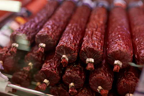 meat products, sale and food concept - salami sausage at grocery store stall