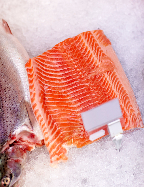 seafood, sale and food concept - chilled fresh salmon fish fillet on ice at grocery store