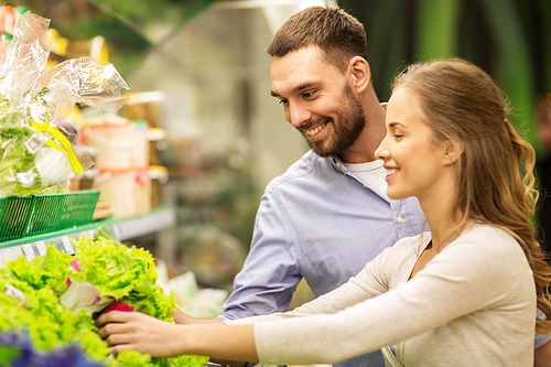 shopping, food, sale, consumerism and people concept - happy couple buying lettuce at grocery store or supermarket