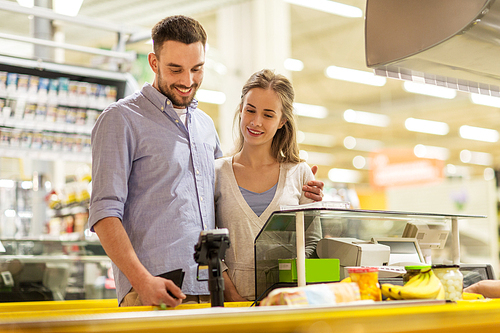 shopping, sale, consumerism and people concept - happy couple buying food at grocery store or supermarket cash register