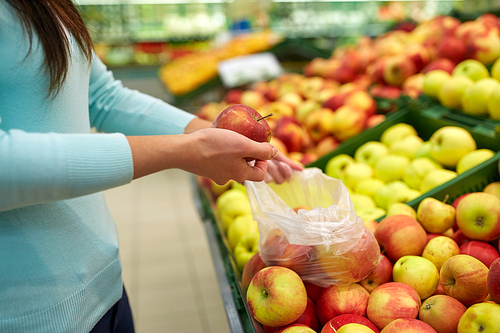sale, shopping, food, consumerism and people concept - woman with bag buying apples at grocery store