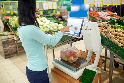 shopping, sale, consumerism and people concept - woman weighing apples on scale at grocery store
