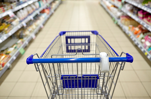 consumerism concept - empty shopping cart or trolley at supermarket