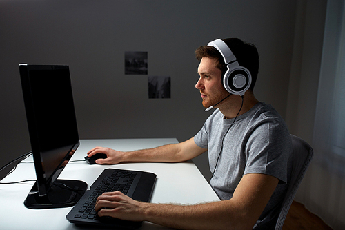 technology, gaming, entertainment, let's play and people concept - young man in headset with pc computer playing game at home and streaming playthrough or walkthrough video