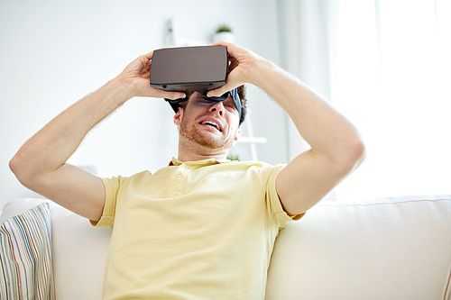 3d technology, virtual reality, gaming, entertainment and people concept - scared young man taking off virtual reality headset or 3d glasses while playing game