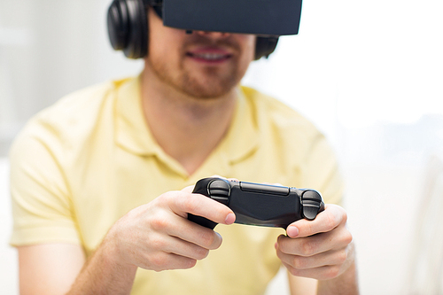 3d technology, virtual reality, gaming, entertainment and people concept - close up of man with virtual reality headset or 3d glasses and headphones playing video game with controller gamepad at home