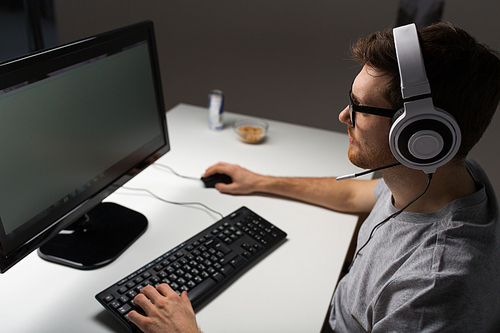 technology, gaming, entertainment, let's play and people concept - close up of young man in headset and glasses with pc computer playing game at home and streaming playthrough or walkthrough video