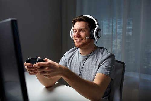 technology, gaming, entertainment, let's play and people concept - happy young man in headset with controller gamepad playing computer game at home and streaming playthrough or walkthrough video