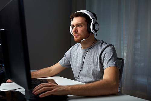 technology, gaming, entertainment, let's play and people concept - young man in headset with pc computer playing game at home and streaming playthrough or walkthrough video