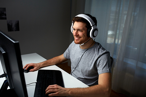 technology, gaming, entertainment, let's play and people concept - happy young man in headset with pc computer playing game at home and streaming playthrough or walkthrough video
