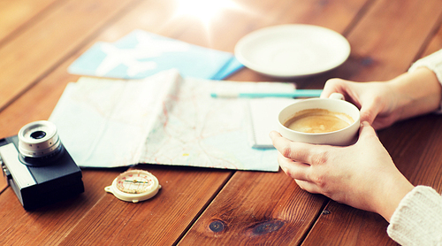 vacation, tourism, travel, destination and people concept - close up of hands with coffee cup and travel stuff