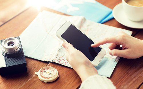 vacation, tourism, travel, technology and people concept - close up of traveler hands with blank smartphone screen and map