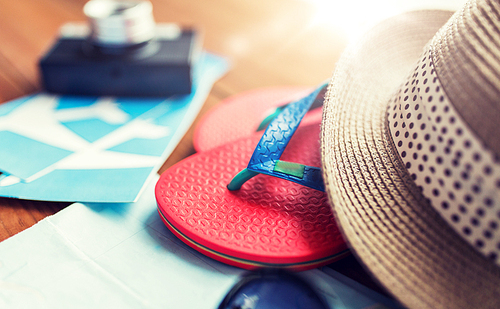 summer vacation, tourism and objects concept - close up of travel map, airplane tickets, flip-flops and hat
