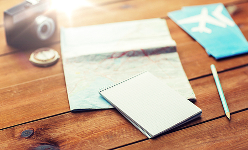 vacation, tourism, travel and objects concept - close up of blank notepad with map and airplane tickets