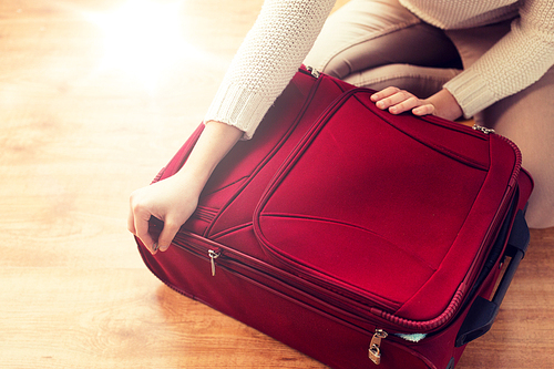 summer vacation, travel, tourism and objects concept - close up of woman packing and zipping travel bag for vacation