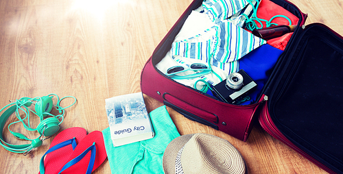 summer vacation, travel, tourism and objects concept - close up of travel bag with clothes and stuff