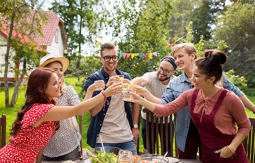summer, holidays, celebration people and food concept - happy friends having garden party and clinking glasses