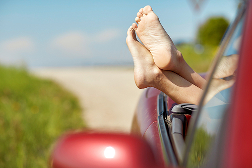 summer vacation, holidays, travel, road trip and people concept - feet of young woman in convertible car