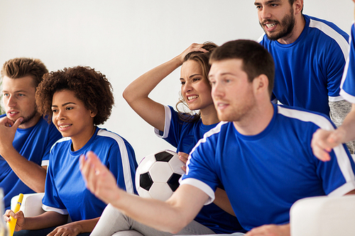 friendship, leisure, sport and entertainment concept - friends or football fans with ball watching soccer at home