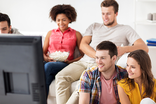 friendship, people and entertainment concept - happy friends with popcorn and beer watching tv at home