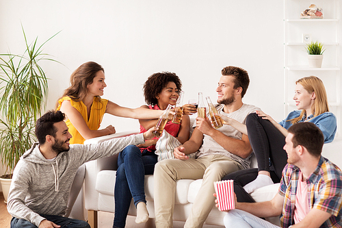 friendship, people and entertainment concept - happy friends with popcorn and beer talking at home
