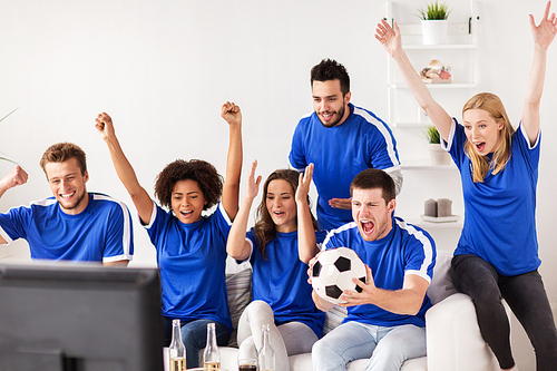 friendship, sport, people and entertainment concept - happy friends or football fans watching soccer and celebrating victory at home