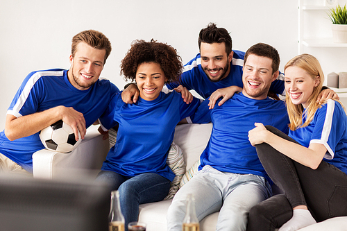 friendship, leisure, sport and entertainment concept - happy friends or football fans with ball watching soccer on tv at home