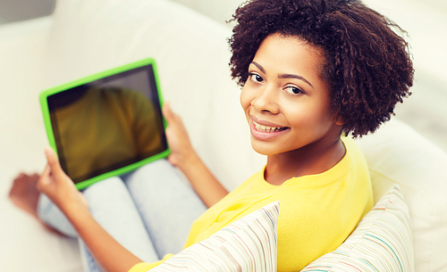 people, technology, advertisement and leisure concept - happy african american young woman sitting on sofa and showing tablet pc computer black blank screen at home