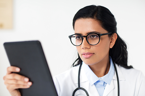 healthcare, technology, people and medicine concept - female doctor in glasses with tablet pc computer at hospital