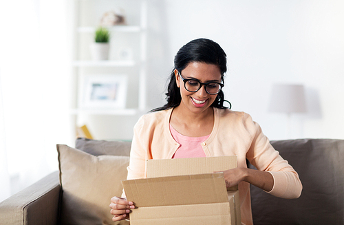 people, delivery, shipping and postal service concept - happy young indian woman holding open cardboard box or parcel at home