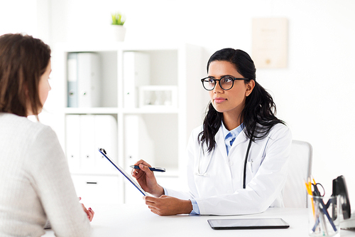 medicine, healthcare and people concept - doctor with clipboard and woman patient at hospital