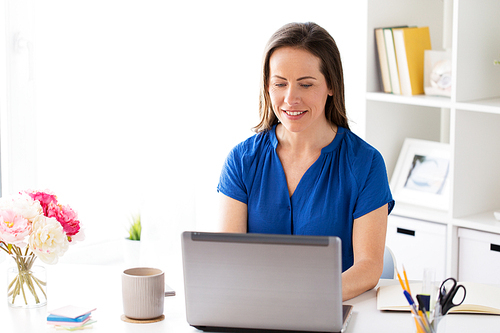 business, people and technology concept - happy smiling woman with laptop computer working at home or office