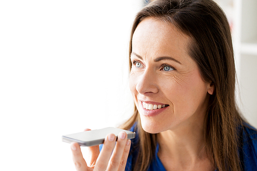 technology, communication and people concept - close up of happy woman using voice command recorder on smartphone