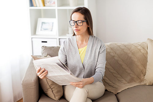 mass media and people concept - happy woman reading newspaper at home