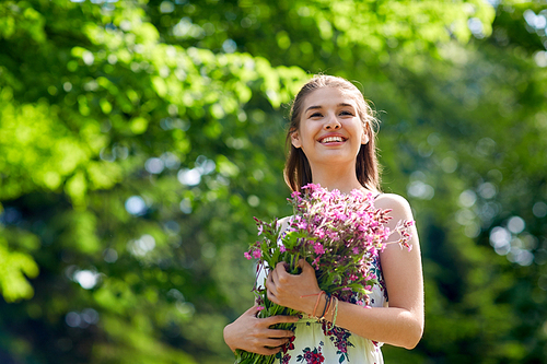 people, leisure and lifestyle concept - happy smiling young woman with flowers in summer park