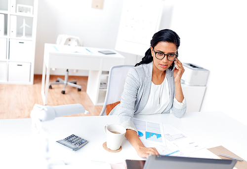 business, technology, communication and people concept - businesswoman with laptop computer papers calling on smartphone at office