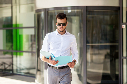 business and people concept - young man in sunglasses with folder on city street