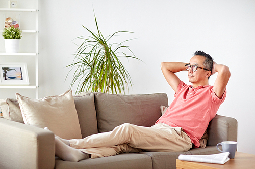 comfort and people concept - man in glasses relaxing on sofa at home